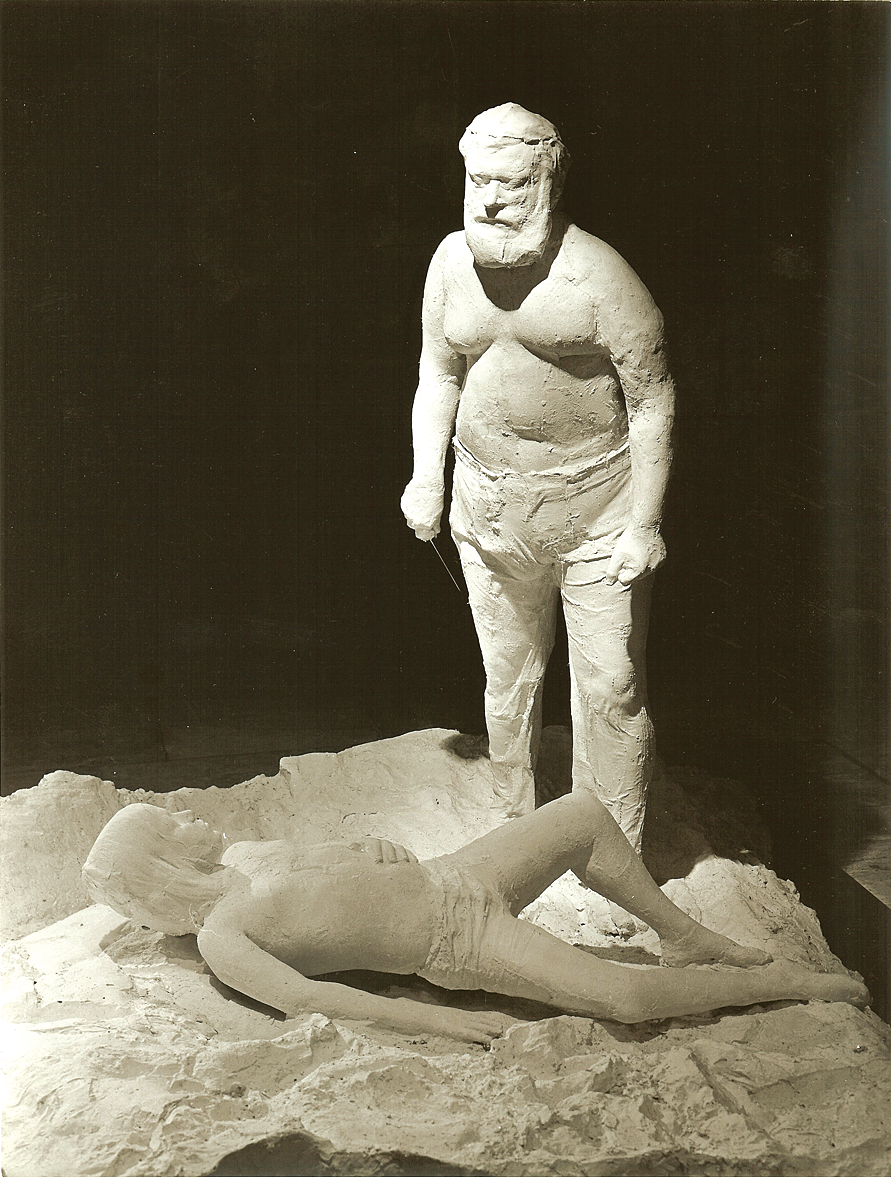 Sculpture of a man standing over a boy lying on his back. 