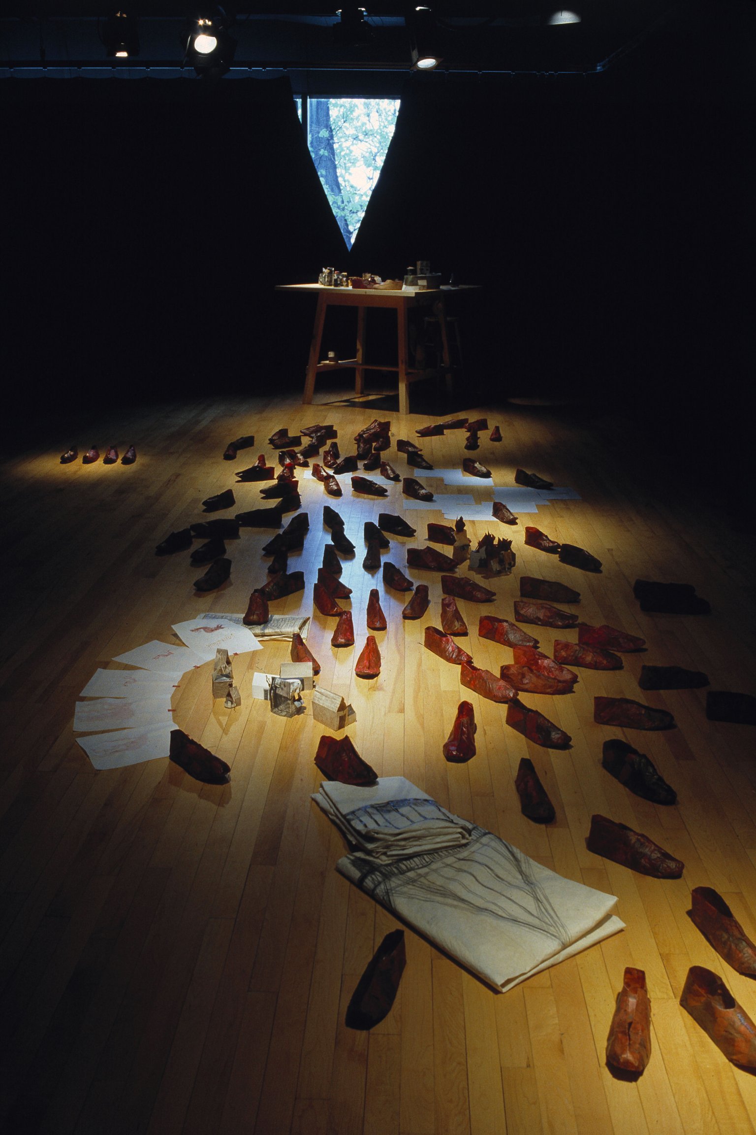 Installation featuring various objects, shoes, and papers on floor. 