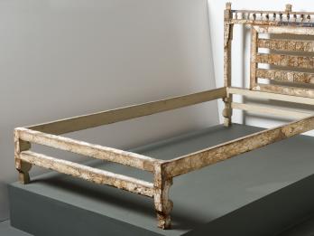 Bed frame decorated with ivory inlay with elaborate carving on headboard.