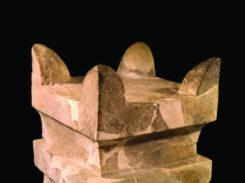 Square limestone altar with horns at four upper corners and recessed band below offering surface.