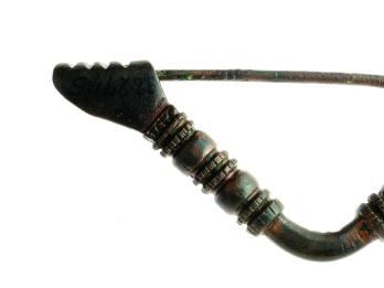 Triangular bronze pin decorated with ornamental bands, with clasp in the shape of a hand.