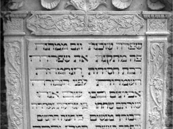 Tombstone of decorative foliage surrounding Hebrew inscription.