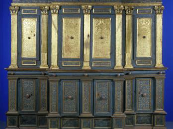 Photograph of ornamental Torah ark chamber with gilded columns and doors with filigree and Hebrew writing. 
