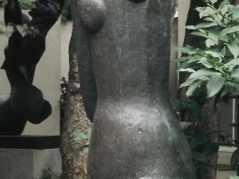 Sculpture of stylized nude woman carrying water over her head.