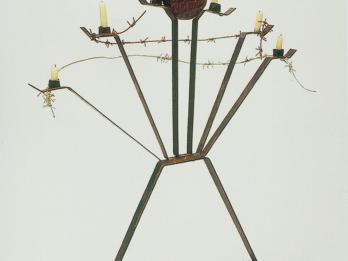 Sculpture of stylized menorah wrapped in barbed wire.