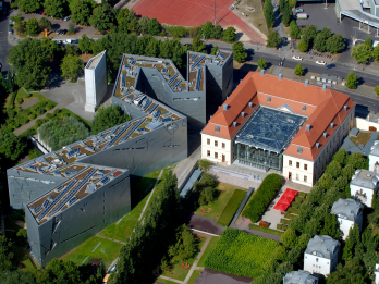 Aerial photograph of angular buildings with trees and grass surrounding. 