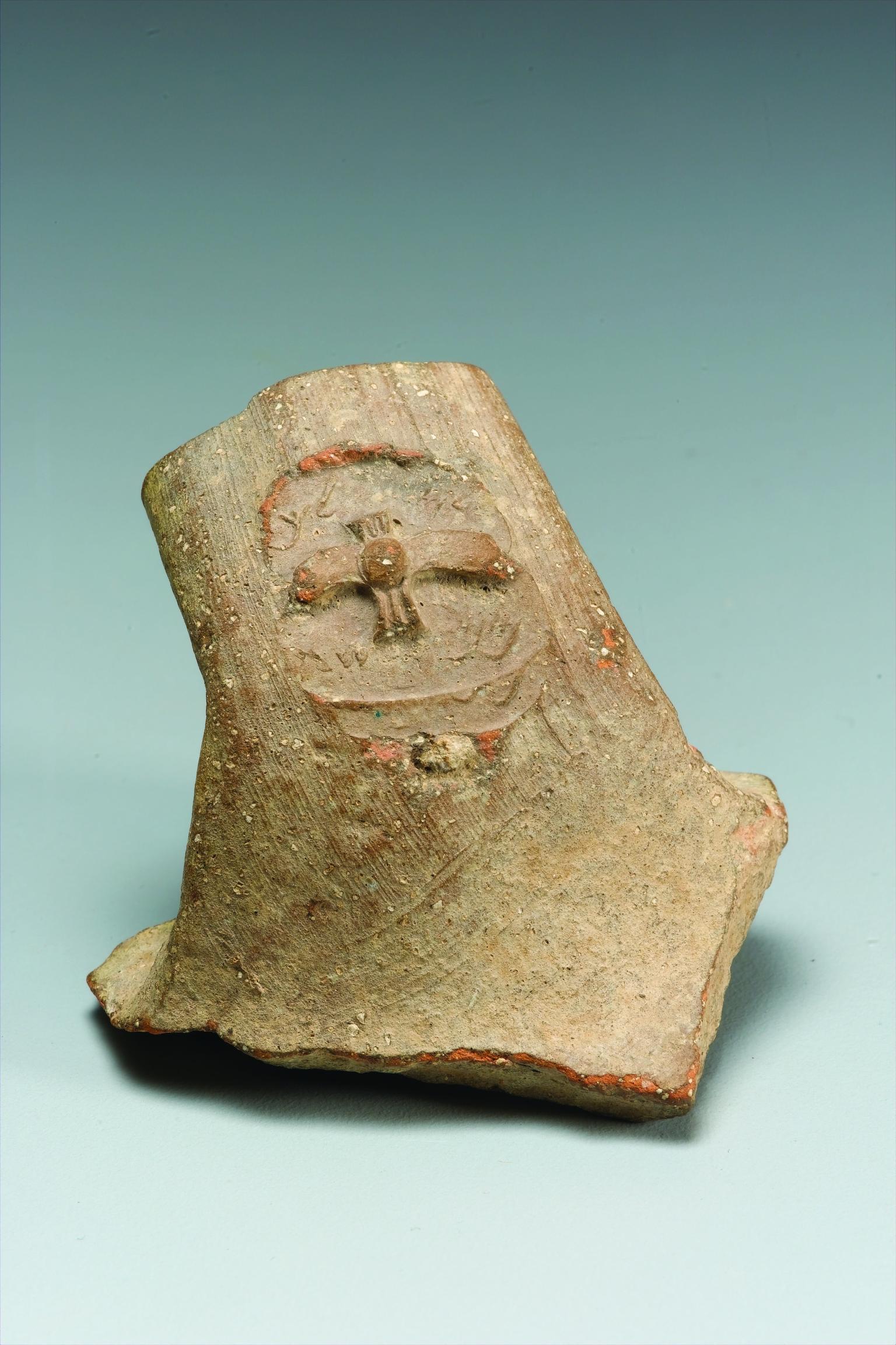Ceramic handle with impression of stylized two-winged figure and Hebrew inscription.