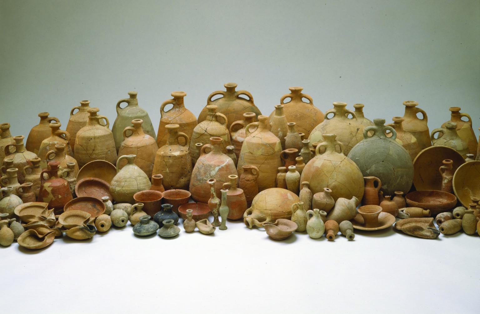 Collection of many ceramic containers including bowls, bottles, decanters, jugs, and oil lamps.