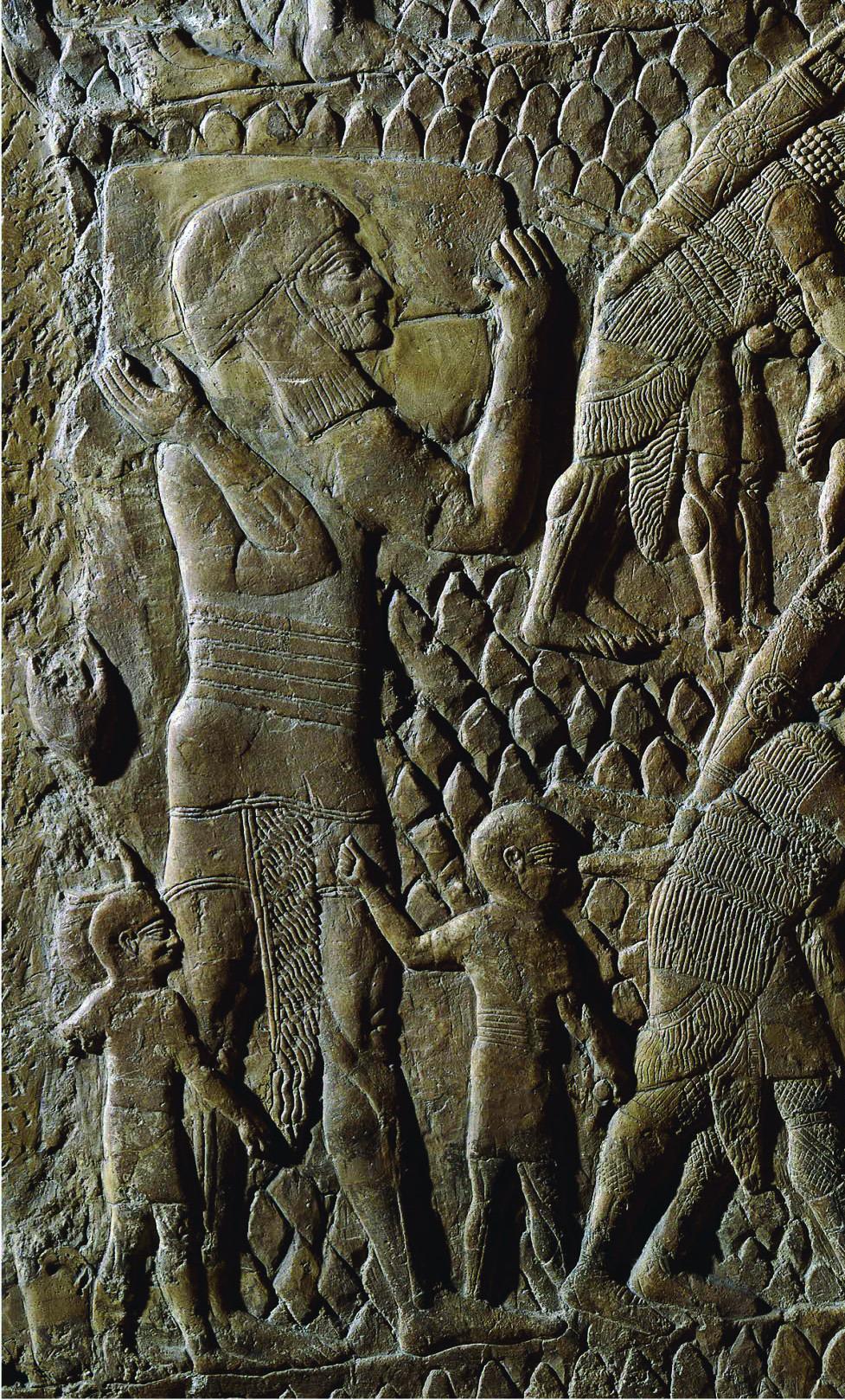 Wall relief of adult male walking with two boys dressed in tunics and caps. 