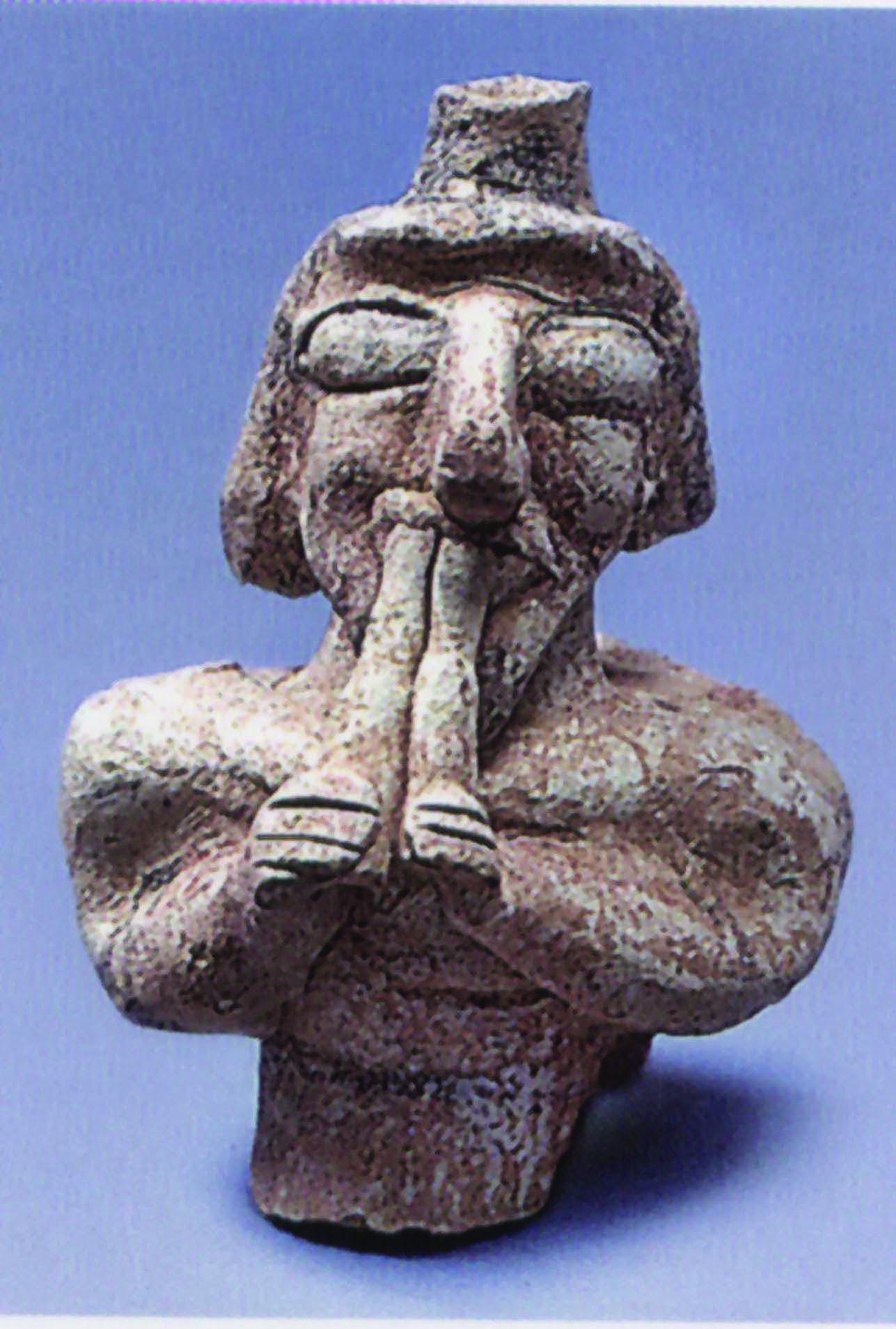 Ceramic figure playing a double pipe.