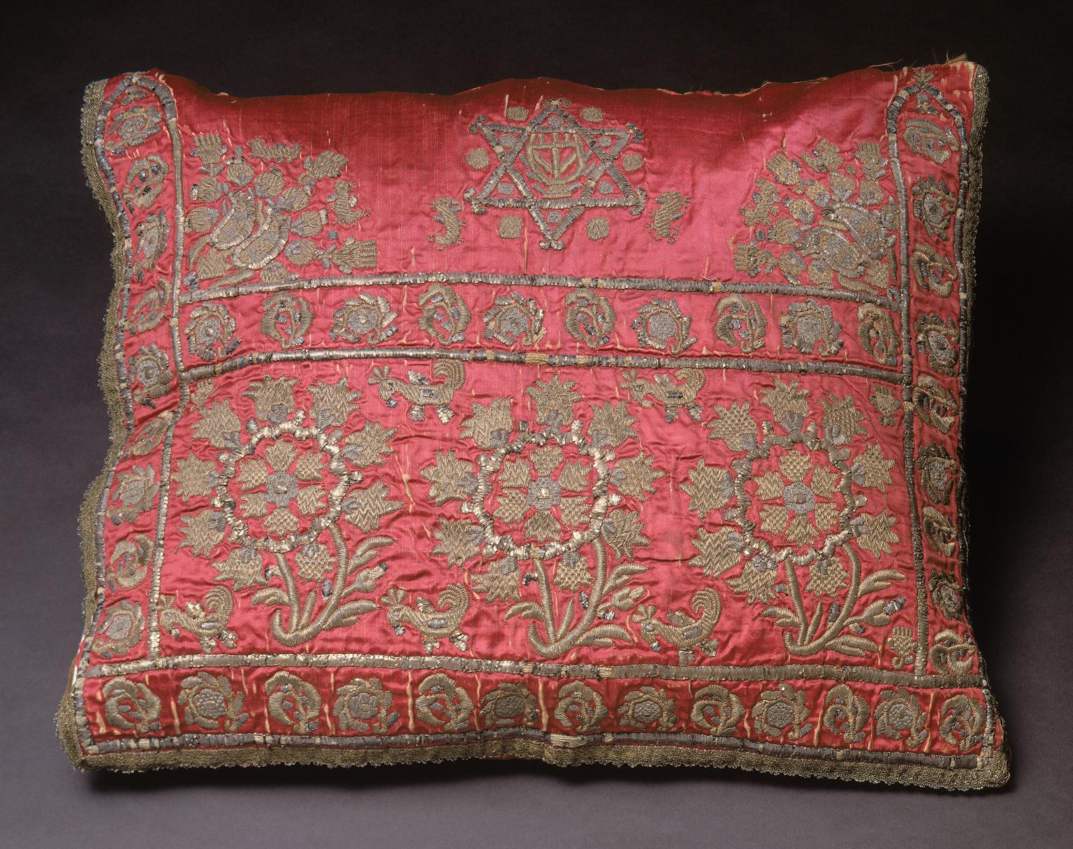 Cushion cover embroidered with Star of David, flowers, and decorative motifs along sides and across middle.