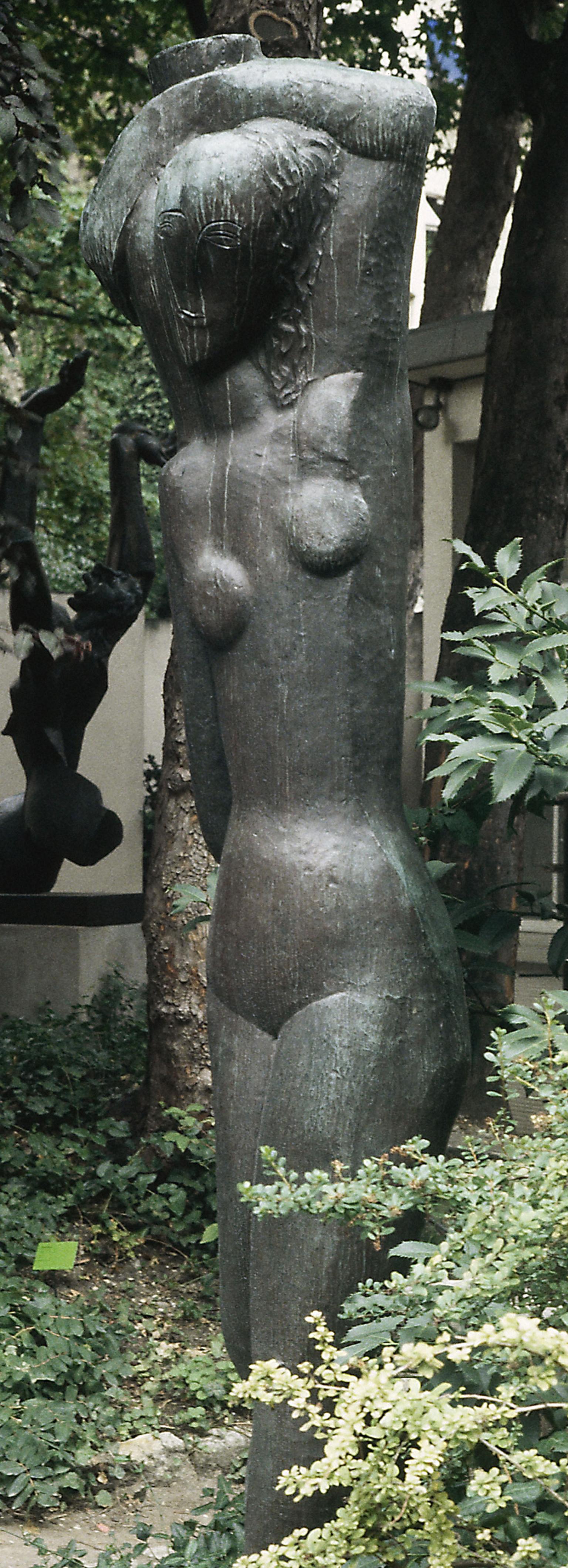 Sculpture of stylized nude woman carrying water over her head.