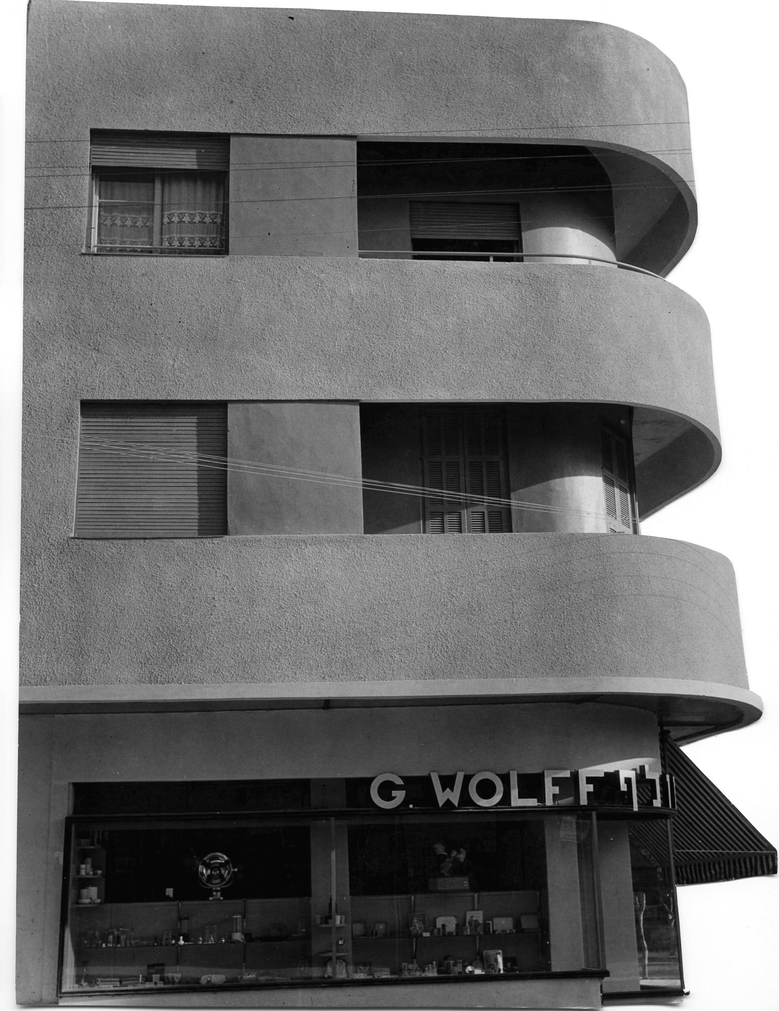 Photograph of side of three-story building exterior featuring sleek, curved balconies.