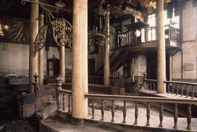 Photograph of room with raised central platform with columns and several chandeliers.