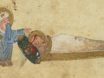 Illustration of a bearded, crying man in a robe and turban, his head surrounded by a gold halo, crouching beside a shrouded figure, also haloed, lying on a wooden bed.