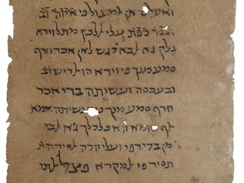 Worn piece of parchment with handwritten text in Hebrew script.