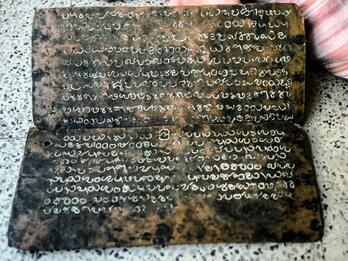 Photo of two mottled horizontal copper plates inscribed with white Mayalayam script.