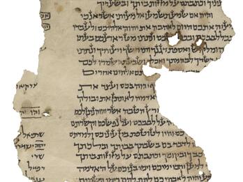 Damaged, irregular manuscript fragment with paragraphs of vowelless Hebrew script, obscured by a torn edge, and, at the other torn edge, a glimpse of a small six-pointed star and more script, some of which is underlined or boxed.