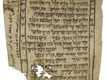 Damaged manuscript page with Hebrew script bordered by a simple frame, with additional text within and beside it.