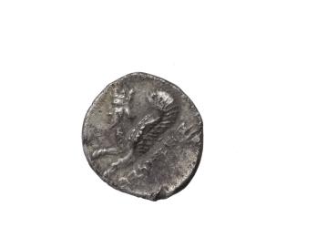 Coin with image of winged creature with human head, beard, and horns and Hebrew inscription.