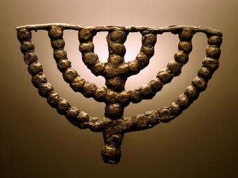 Ancient bronze menorah with seven branches, crafted from round beads forming its shape.