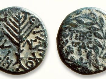 Two sides of an ancient bronze coin: one shows a stylized palm branch surrounded by Greek text, and the other has a wreath with Greek text inside.