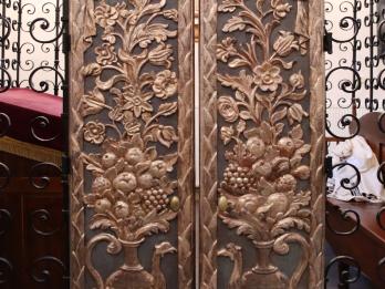 Set of curved doors with carving of peacock-shaped pitcher filled with foliage and fruit extending to top of door. 
