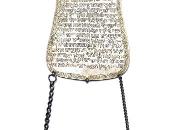 Plaque with Hebrew text and two chains hanging from the bottom.