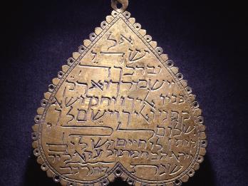 Heart-shaped amulet with Hebrew words.