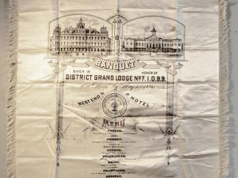 Cloth with image of buildings and menu in English printed on it.