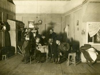 Photograph of figures sitting in furnished room.