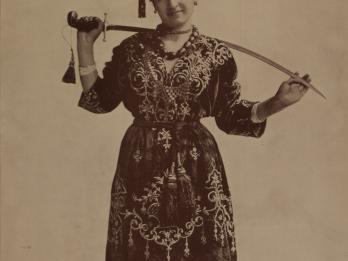 Photograph of figure holding sword behind her neck.