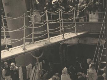 Photograph of a ship deck with two stories filled with people.