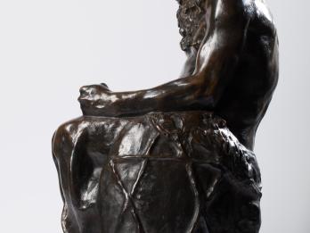 Bronze sculpture of seated figure with beard and Star of David etched onto its side.