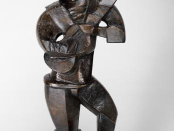 Sculpture of abstract figure standing and holding a guitar.