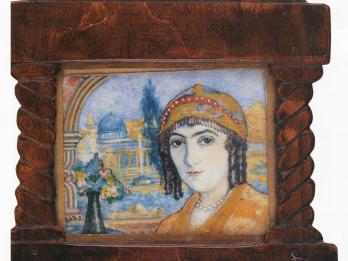 Framed painting of woman facing viewer, wearing beaded head covering, with domed building in background, and Hebrew word on frame underneath portrait.