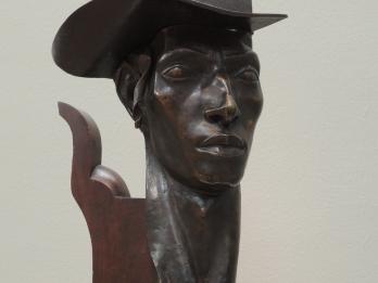Bust of man wearing a hat.