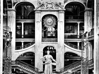 Photograph depicting tall statue in the center of large atrium with interior staircases.