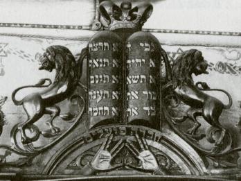 Photograph of wooden structure with two small columns of Hebrew writing with crown on top, and two sculped lions on either side.
