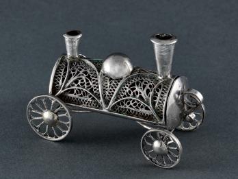 Filigree container in shape of a train car with four wheels and two smoke stacks.