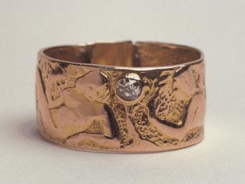 Gold wedding ring stamped with two figures and inlaid with a diamond.