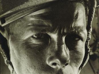Portrait photograph of soldier wearing helmet and stern expression.