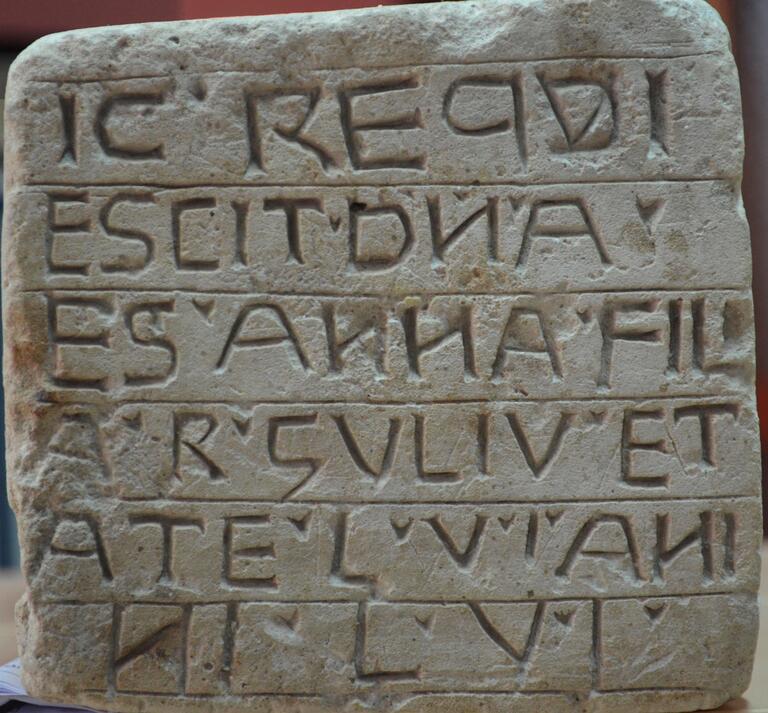 Upright stone slab engraved with ten rows of vowelless Hebrew roughly inscribed and separated by lines.