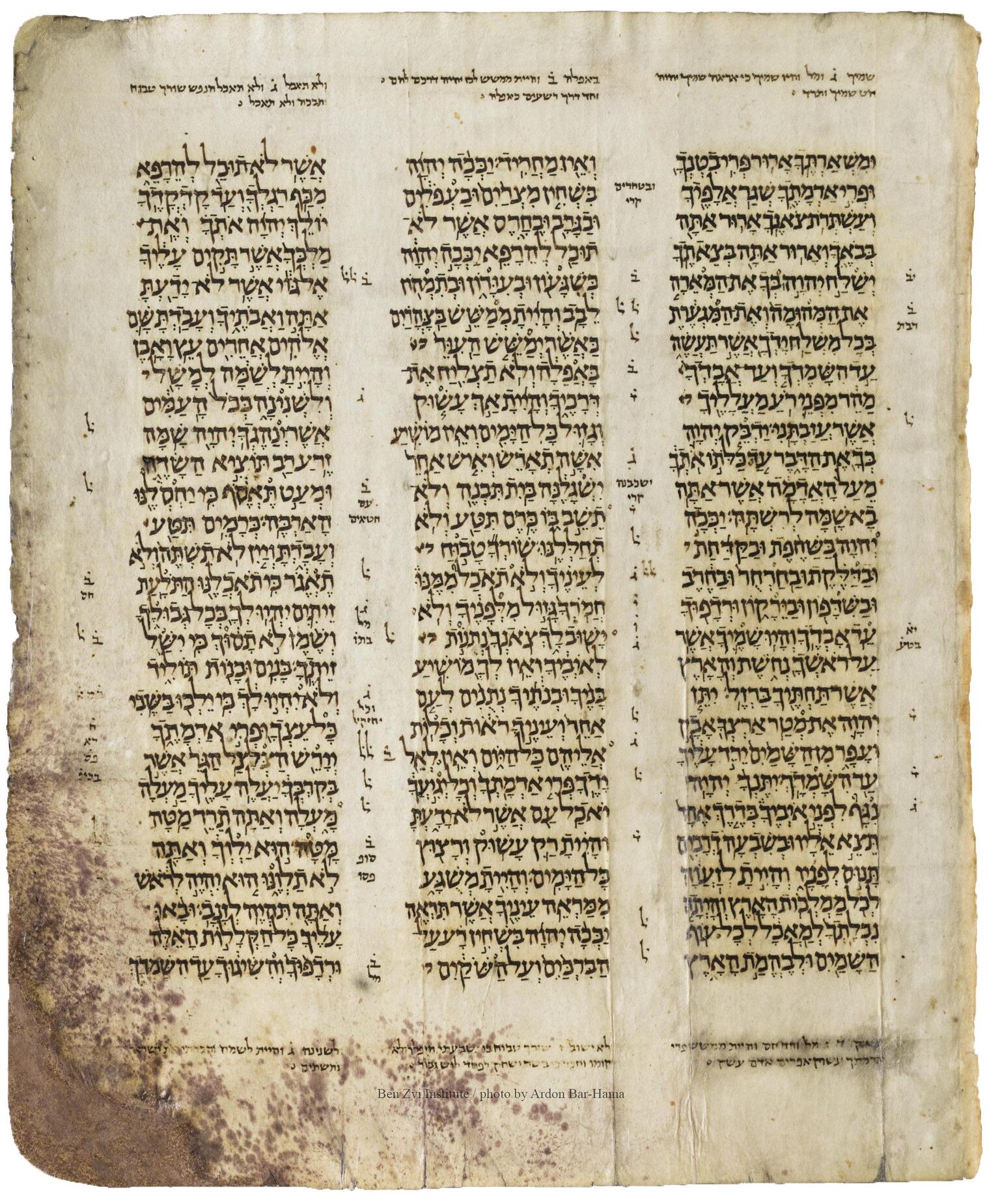 Manuscript page with three columns of Hebrew text, with smaller writing in the margins and between columns.