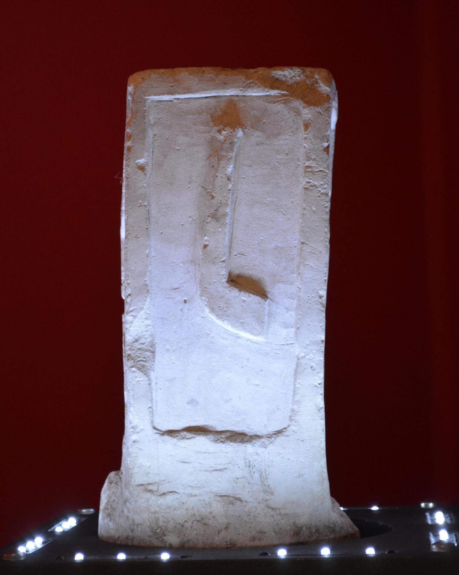 Photo of a weathered square stone slab inscribed with six lines of Latin.