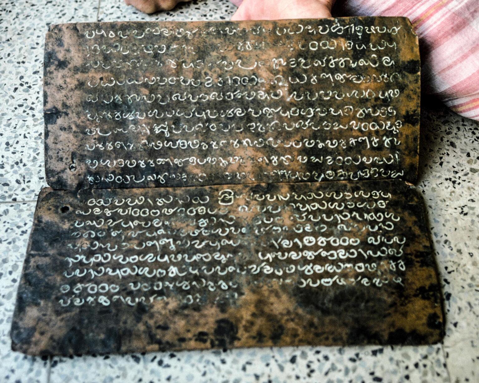 Photo of two mottled horizontal copper plates inscribed with white Mayalayam script.