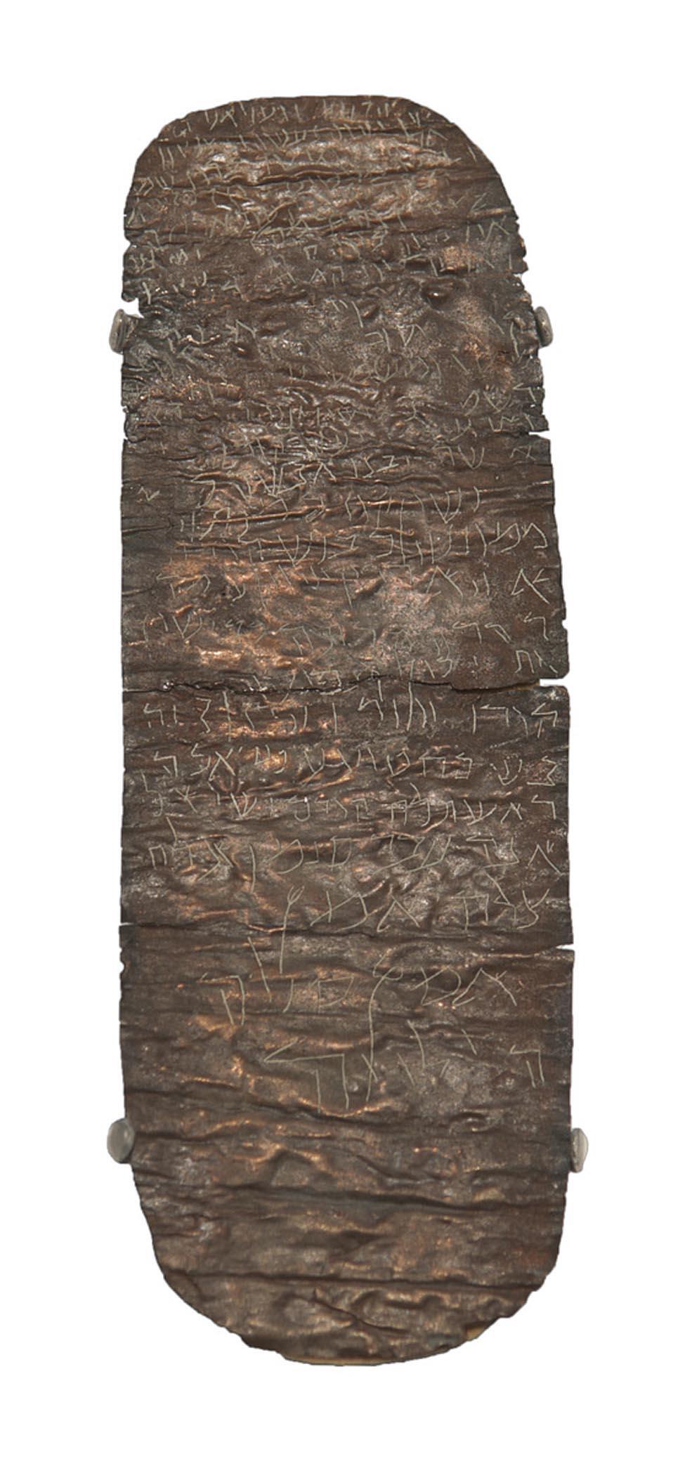 Oblong piece of metal with rough surface and Hebrew script etched into it.