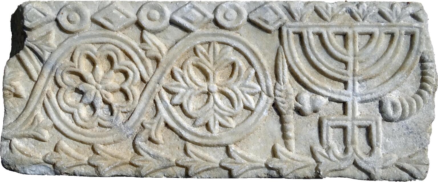 Stone relief with a candelabrum, horn, and plant bundle, floral patterns, and floral and geometric borders.
