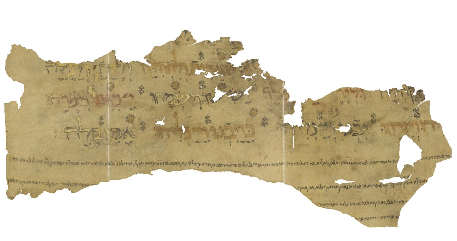 Irregular fragment of tattered manuscript with Hebrew lettering alternating between black, red, and gold, with vowels in black outline, and with small decorations disprersed among the words and smaller, vowelless lines of text below.