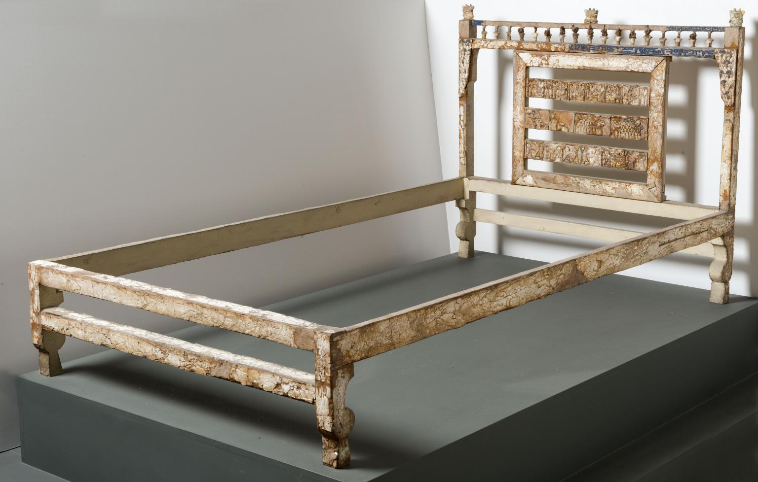 Bed frame decorated with ivory inlay with elaborate carving on headboard.